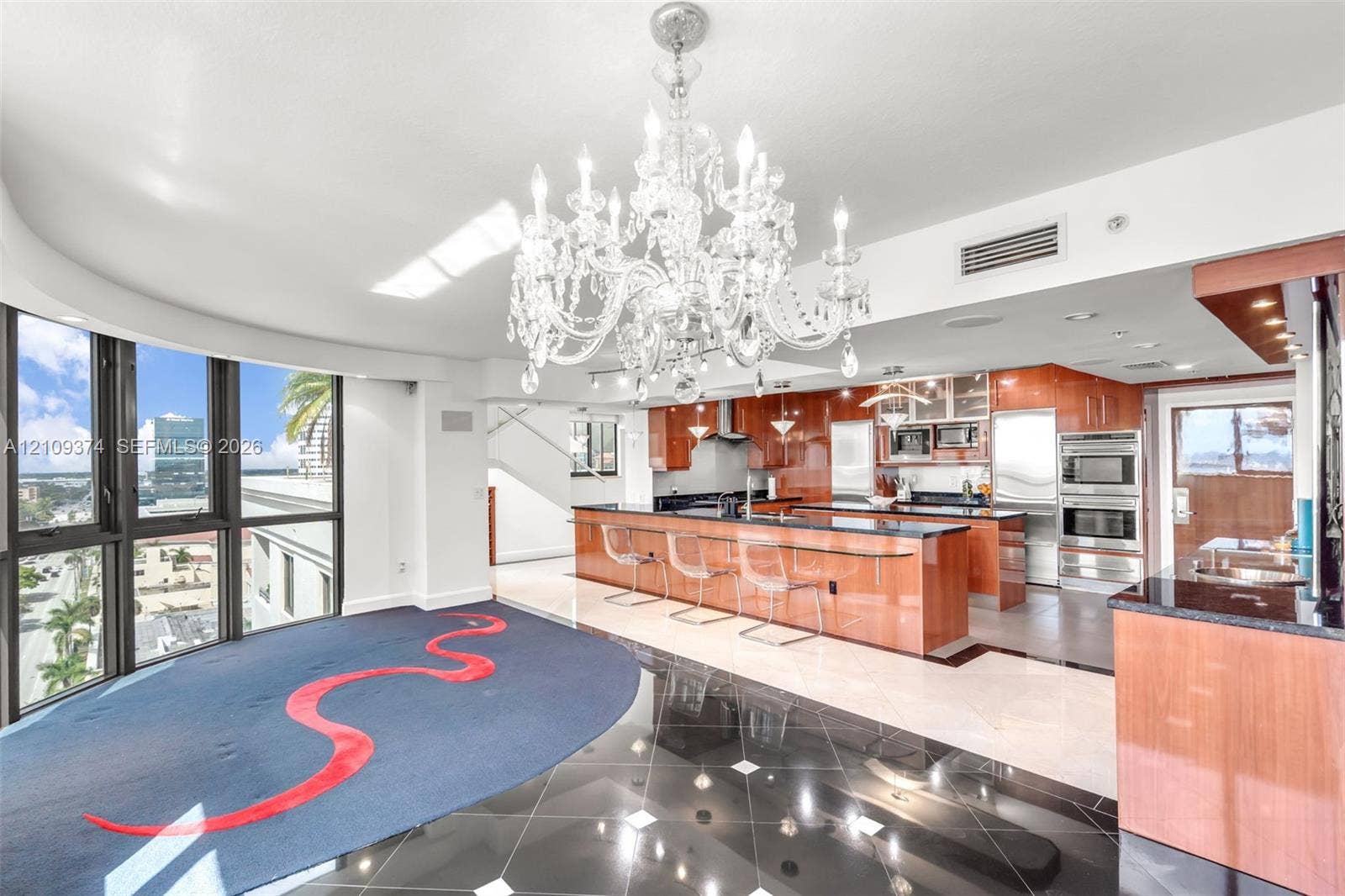 100 N Federal Highway, #1, Fort Lauderdale, FL 33301 Kitchen featuring high-gloss wood cabinetry, dark stone countertops, built-in stainless steel appliances, a large center island, and an ornate crystal chandelier