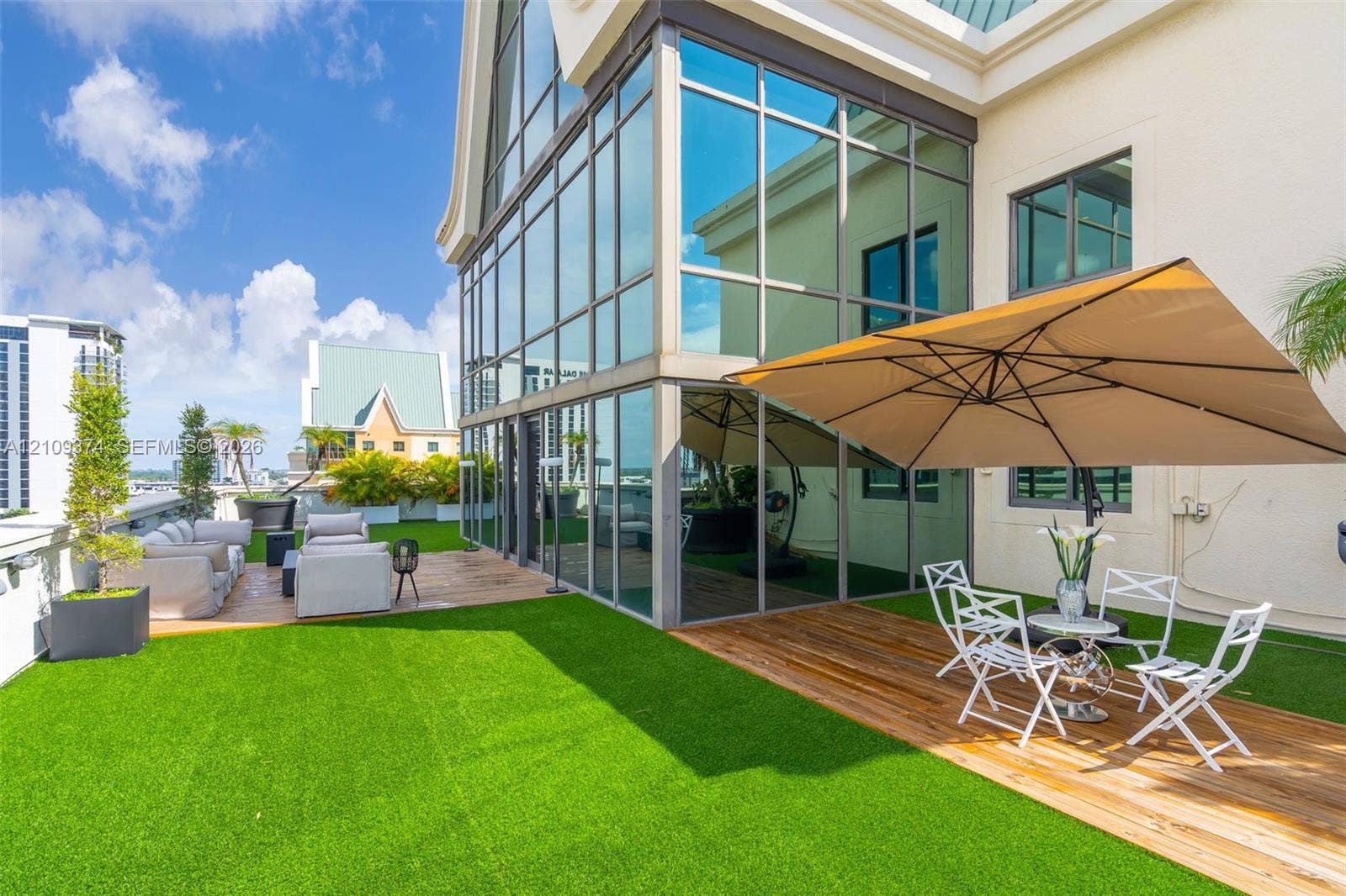 100 N Federal Highway, #1, Fort Lauderdale, FL 33301 Expansive rooftop terrace featuring floor-to-ceiling glass wall panels, synthetic turf lawn, wood-finish decking, and light-colored stucco exterior siding