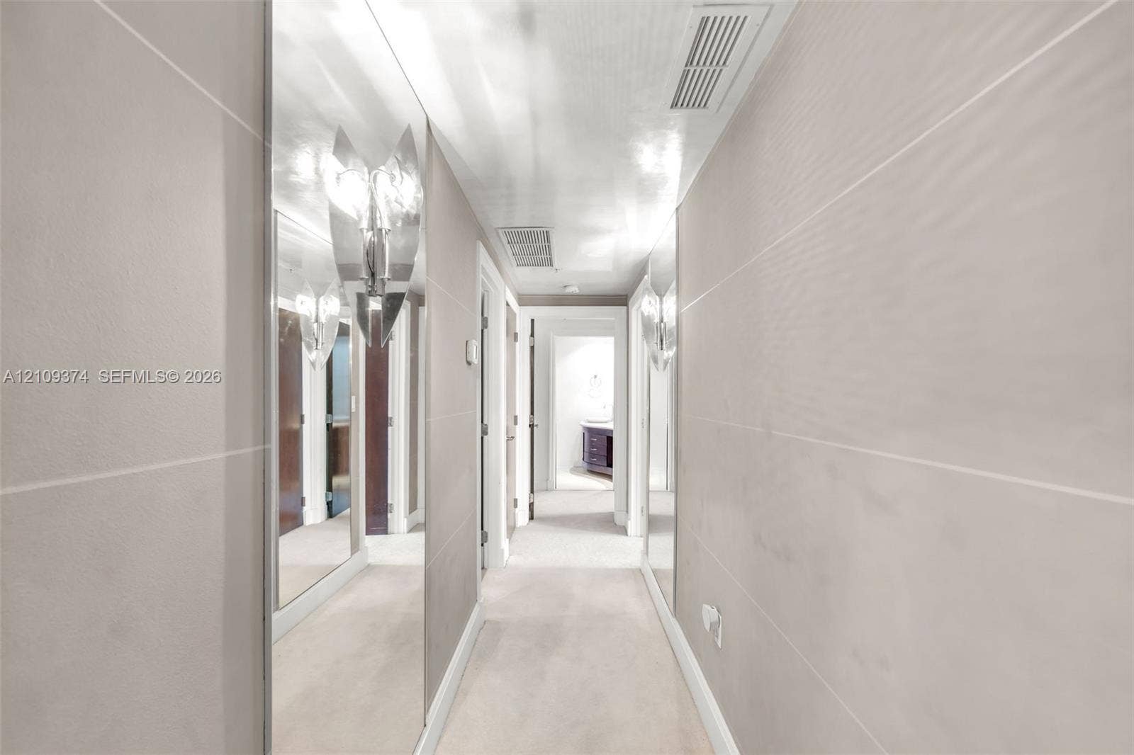 100 N Federal Highway, #1, Fort Lauderdale, FL 33301 Hallway featuring large-format light-toned wall tile, floor-to-ceiling mirror panels, and dual metallic wall-mounted sconces