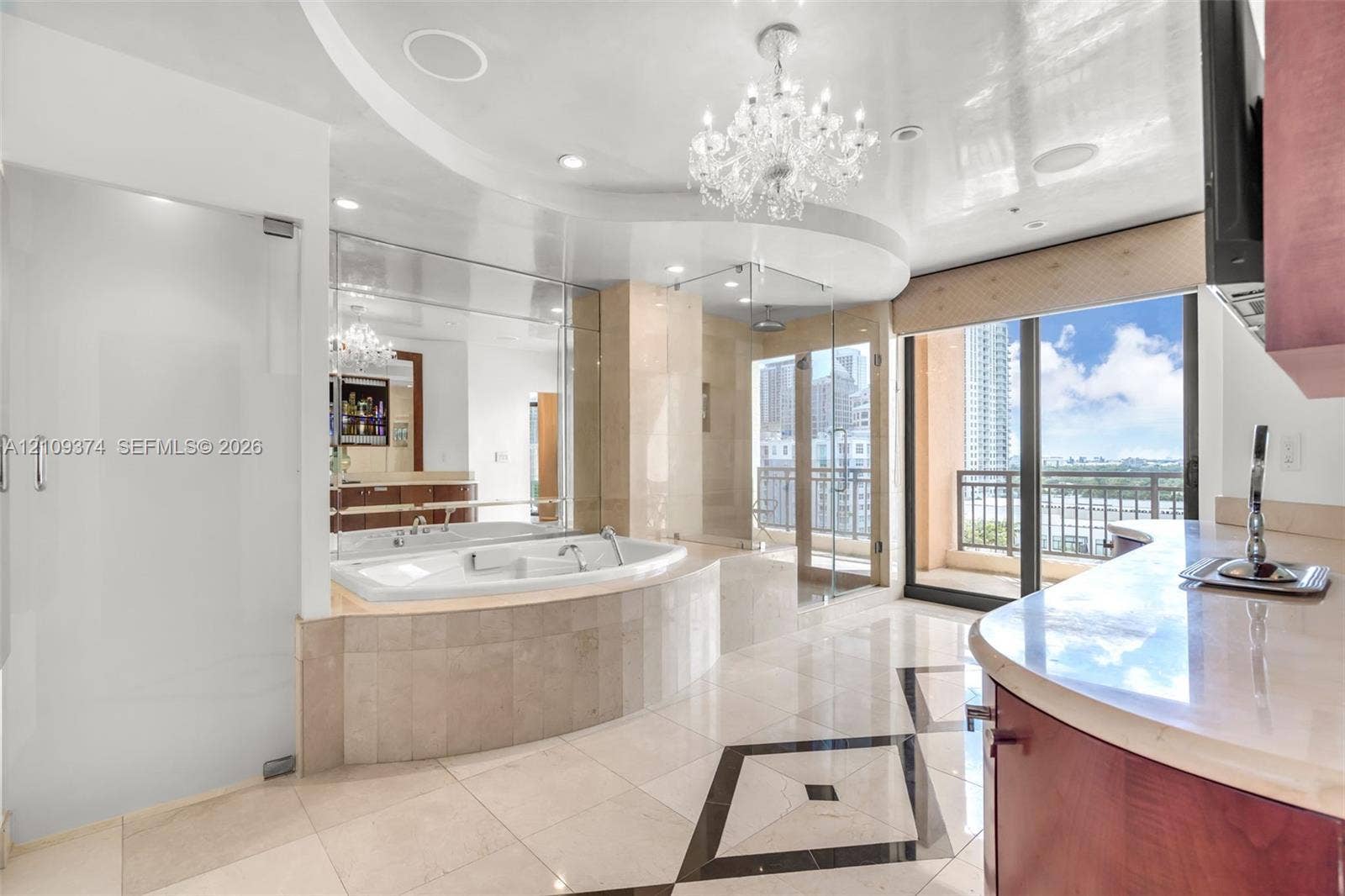 100 N Federal Highway, #1, Fort Lauderdale, FL 33301 Soaking tub with stone surround, glass-enclosed shower, expansive vanity with stone countertop, ornate chandelier, and polished tile flooring with geometric inlay