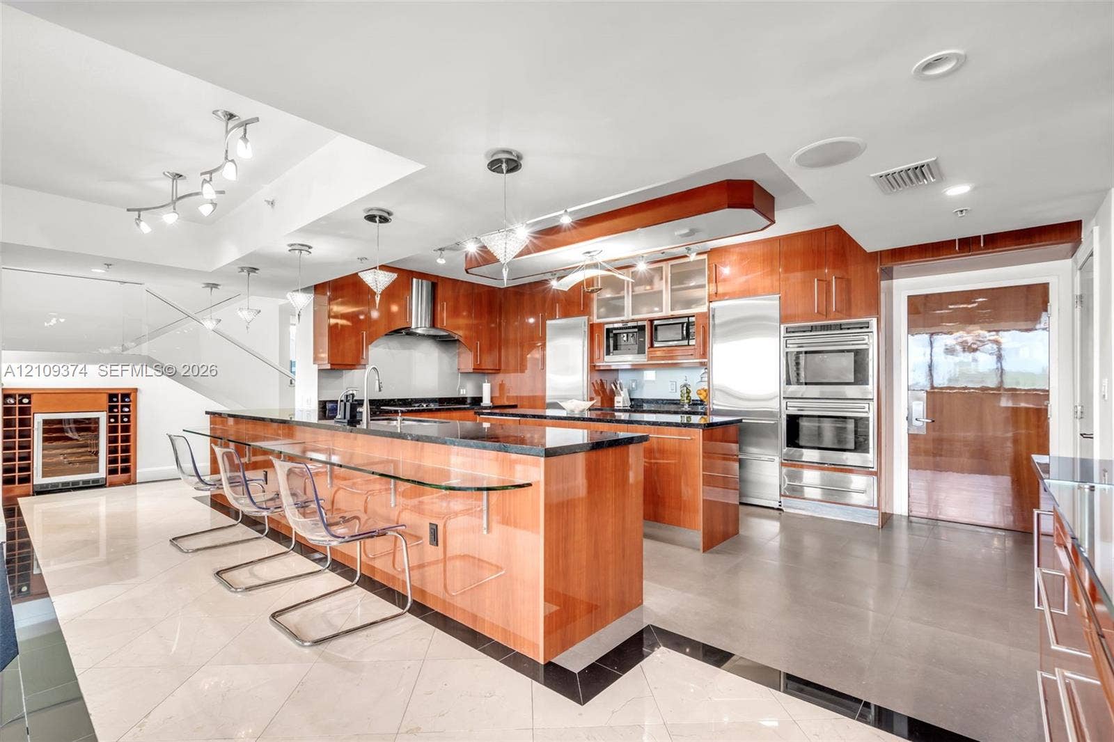 100 N Federal Highway, #1, Fort Lauderdale, FL 33301 Gourmet kitchen featuring high-gloss wood cabinetry, dark stone countertops, integrated stainless steel appliances, a glass-top breakfast bar, and polished tile flooring