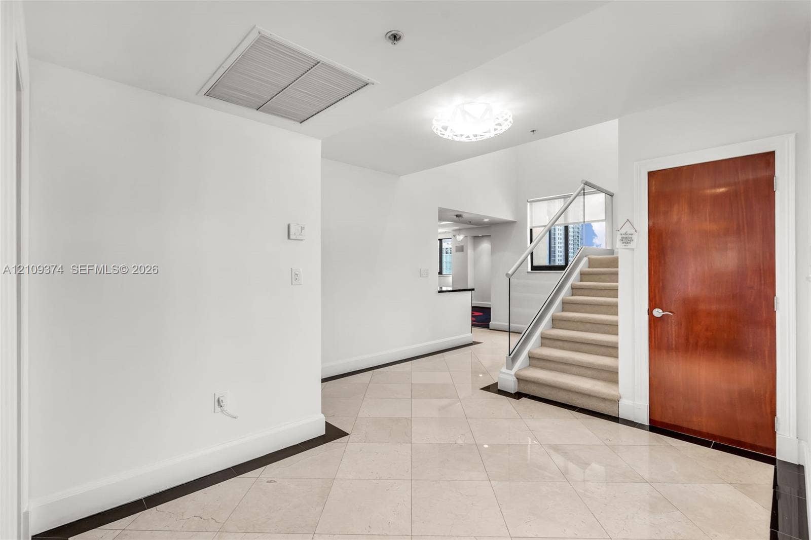 100 N Federal Highway, #1, Fort Lauderdale, FL 33301 Entryway featuring large-format diagonal tile flooring, a solid wood-finish entry door, a staircase with a glass panel railing, and a decorative circular ceiling light fixture