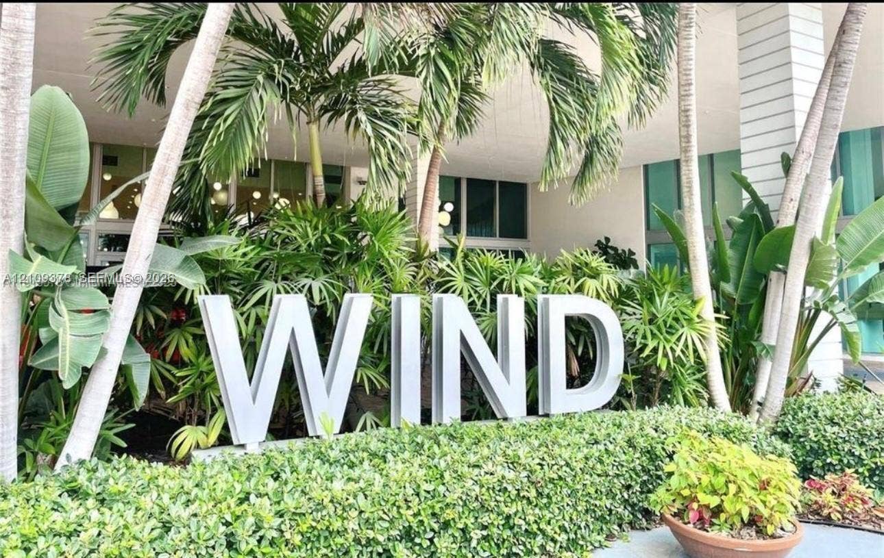 350 S Miami Avenue, #2207, Miami, Miami, FL 33130 Exterior building signage featuring dimensional lettering nestled within mature tropical landscaping, including palm trees and manicured shrubbery