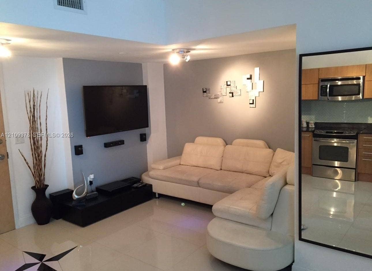 350 S Miami Avenue, #2207, Miami, Miami, FL 33130 Living space featuring high ceilings, large-format tile flooring, and a kitchen equipped with wood cabinetry and stainless steel appliances