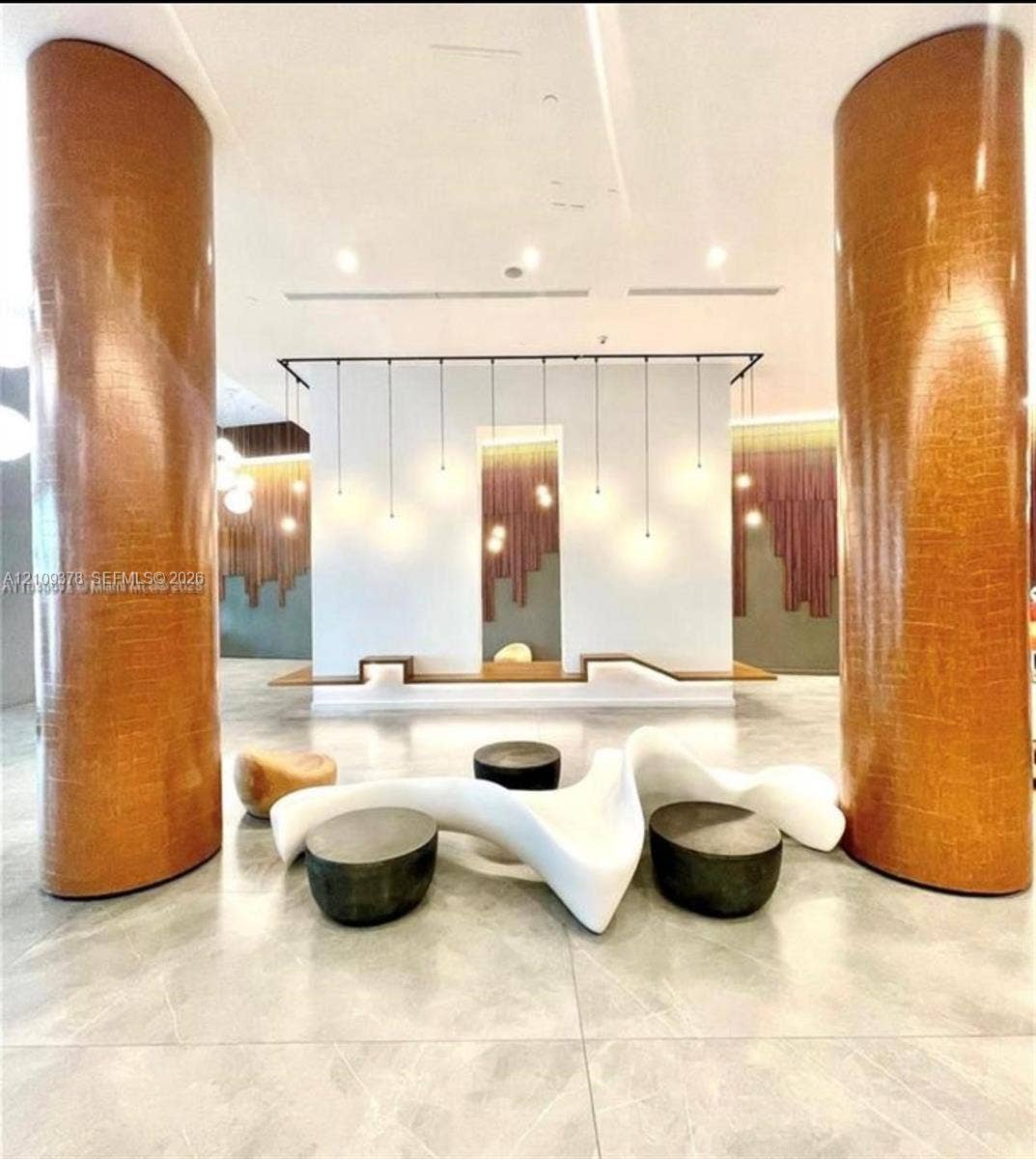 350 S Miami Avenue, #2207, Miami, Miami, FL 33130 Large-scale textured metallic columns, polished tile flooring, recessed ceiling lighting, custom wall-integrated wood seating, and vertical pendant lighting fixtures