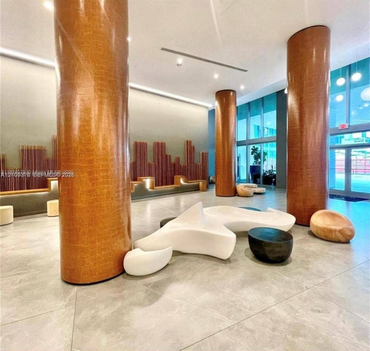 350 S Miami Avenue, #2207, Miami, Miami, FL 33130 Lobby featuring floor-to-ceiling textured structural columns, large-format tile flooring, recessed cove lighting, and a linear wall installation with integrated accent lighting