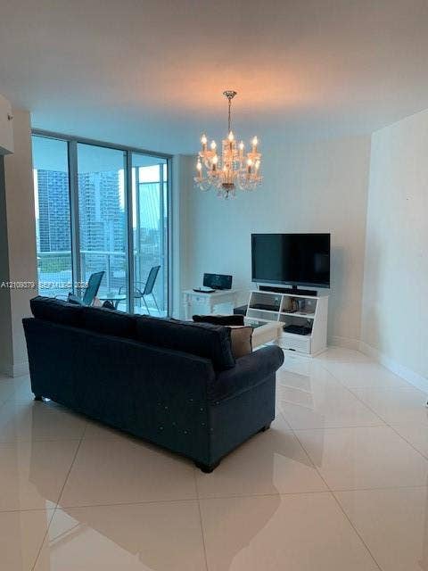 Large-format polished tile flooring, floor-to-ceiling glass panel windows, and crystal chandelier fixture