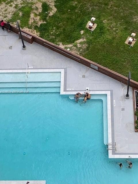 Swimming pool featuring stepped entry, tile coping, metal handrails, and surrounding concrete decking with wood-slat fencing