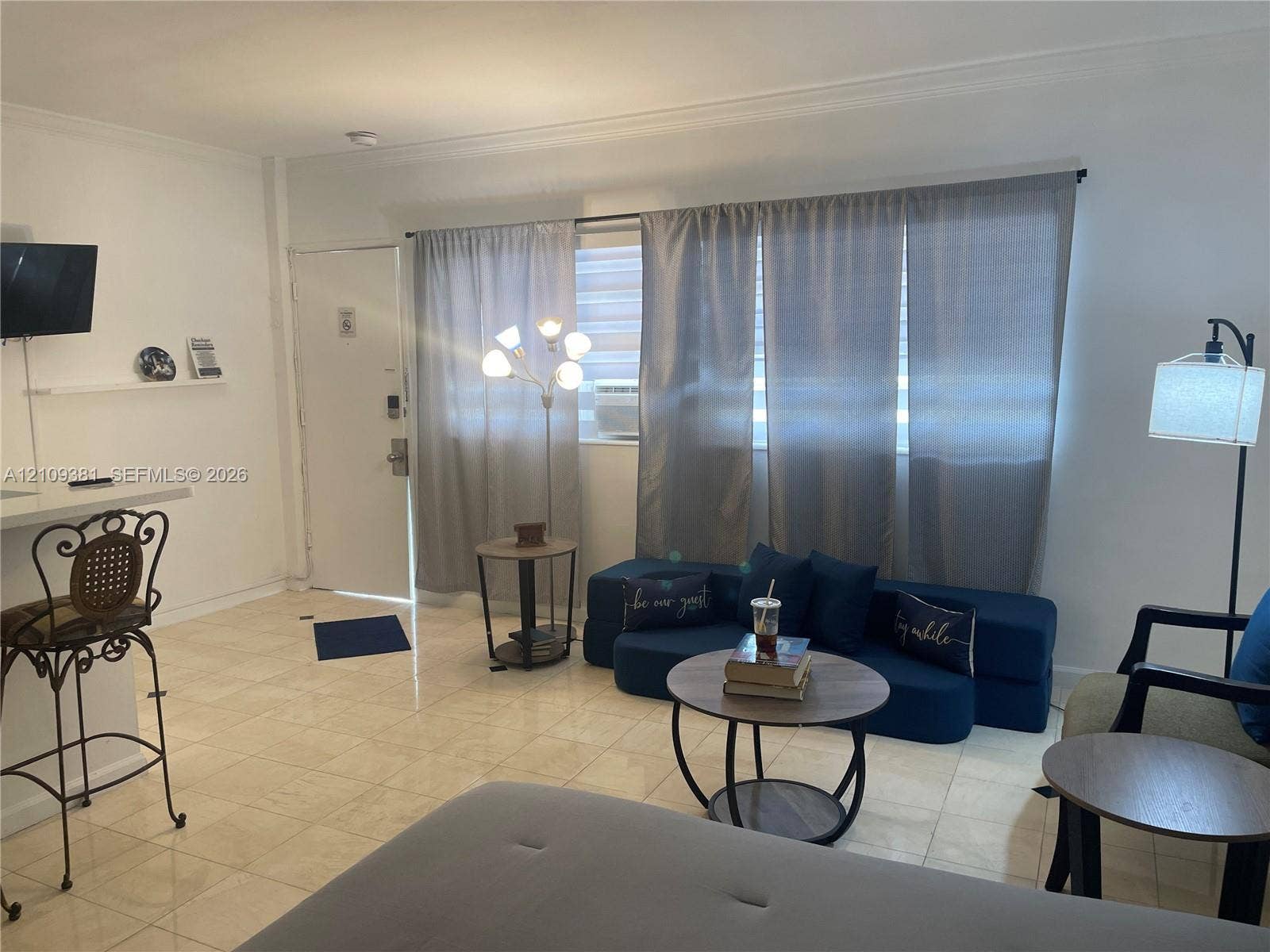 26 Diplomat Parkway, #2351, Hallandale Beach, FL 33009 Kitchenette featuring glossy white cabinetry, solid-surface countertops, an undermount stainless steel sink with a goose-neck faucet, and a black full-size refrigerator