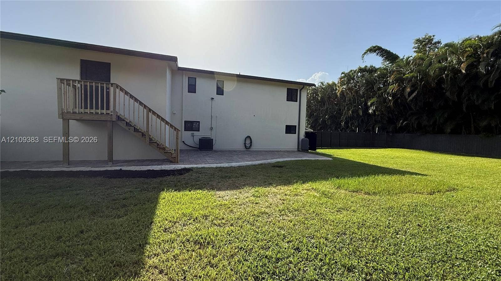 10751 SW 48th Street, Davie, Davie, FL 33328 Backyard featuring an expansive lawn, paver patio, wood-railing exterior staircase, and perimeter fencing