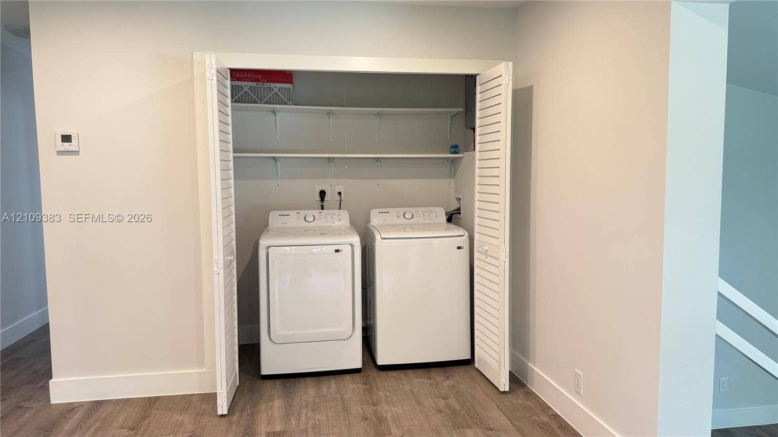 10751 SW 48th Street, Davie, Davie, FL 33328 Laundry closet featuring white louvered bifold doors, wood-finish flooring, and built-in upper shelving