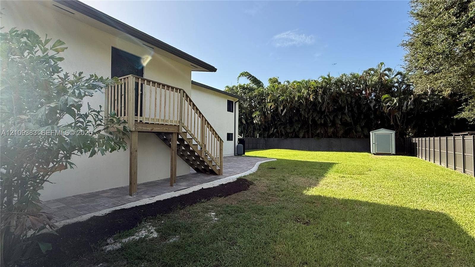 10751 SW 48th Street, Davie, Davie, FL 33328 Expansive backyard featuring a manicured lawn, paved patio, wood-construction exterior staircase, and perimeter fencing