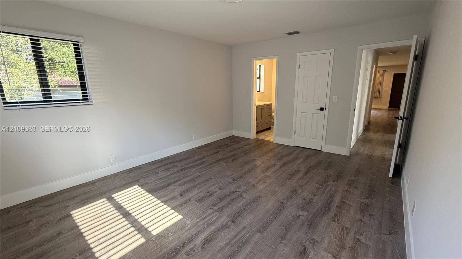 10751 SW 48th Street, Davie, Davie, FL 33328 Neutral-toned interior featuring wood-finish flooring, a single-hung window, and a white six-panel interior door