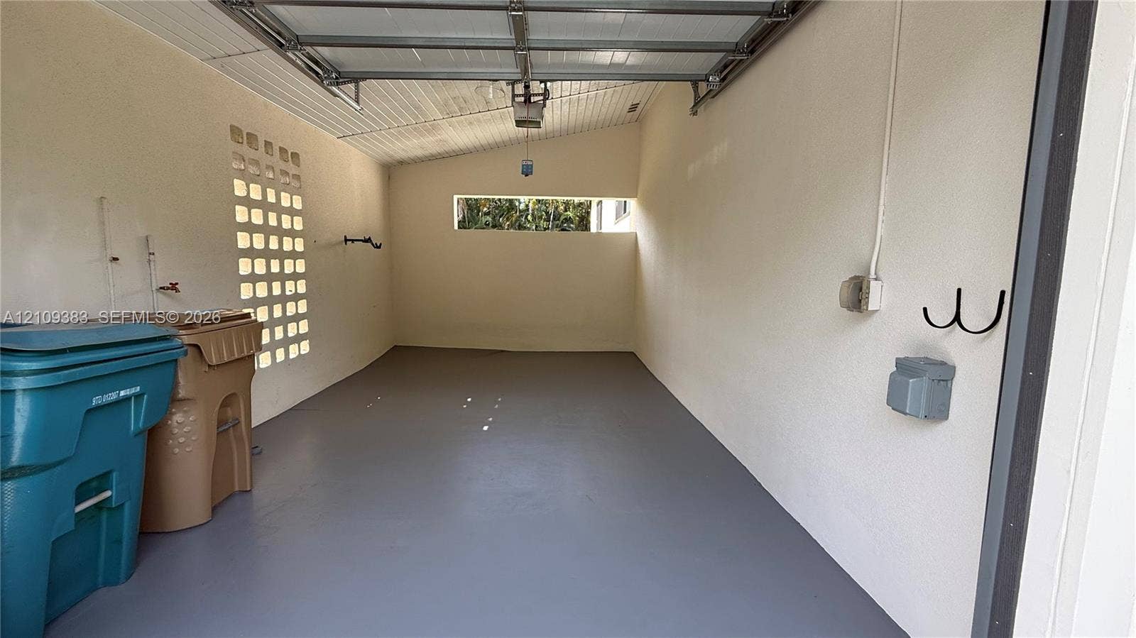 10751 SW 48th Street, Davie, Davie, FL 33328 Enclosed garage featuring a concrete floor, textured wall finish, integrated glass block masonry, and horizontal clerestory window