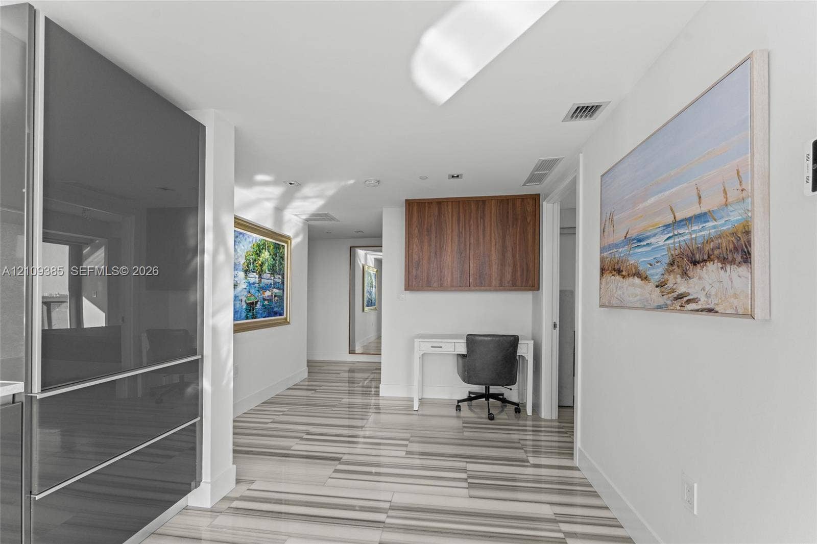Glossy charcoal cabinetry, wood-finish wall-mounted cabinetry, and large-format tile flooring