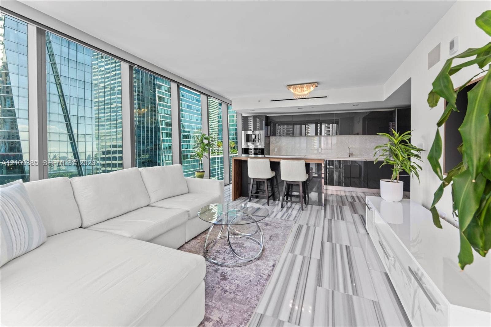 Floor-to-ceiling windows, high-gloss cabinetry, linear-patterned tile flooring, integrated kitchen appliances, and stone-topped kitchen island