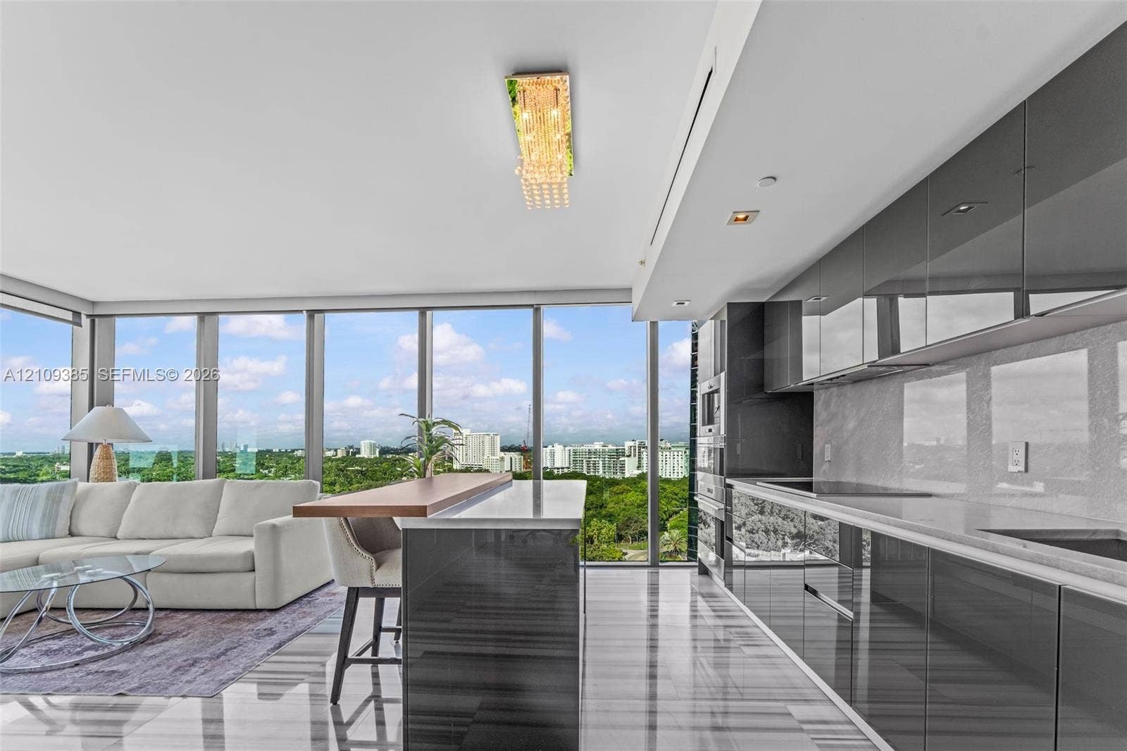 Kitchen featuring high-gloss cabinetry, stone countertops, integrated appliances, floor-to-ceiling windows, and polished stone flooring