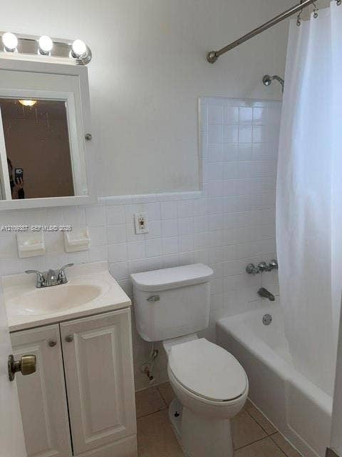 Bathroom featuring a white vanity cabinet, ceramic tile tub surround, chrome-finished plumbing fixtures, and wall-mounted vanity lighting