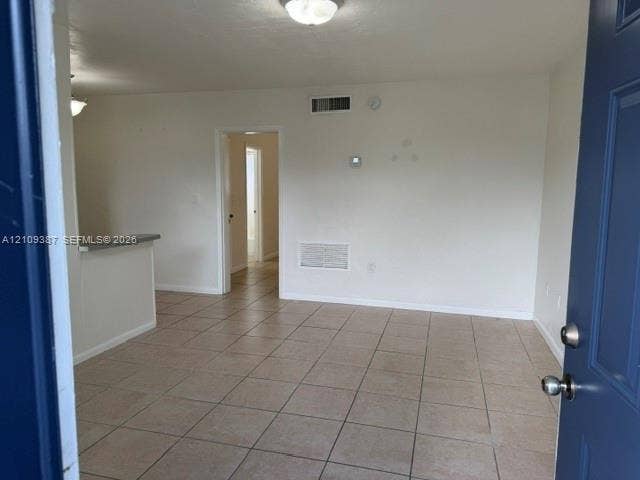 Interior space featuring neutral-toned tile flooring, recessed ceiling lighting, and a breakfast bar