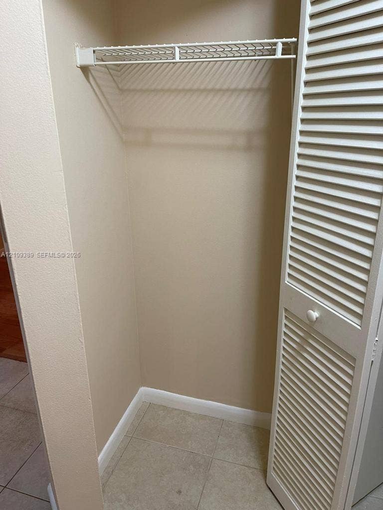 Reach-in closet featuring white louvered bi-fold doors and a built-in wire storage shelf
