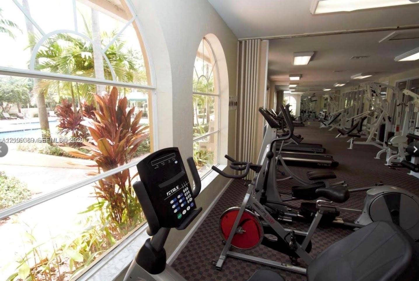 Fitness center featuring floor-to-ceiling arched windows, patterned wall-to-wall carpeting, and recessed ceiling lighting