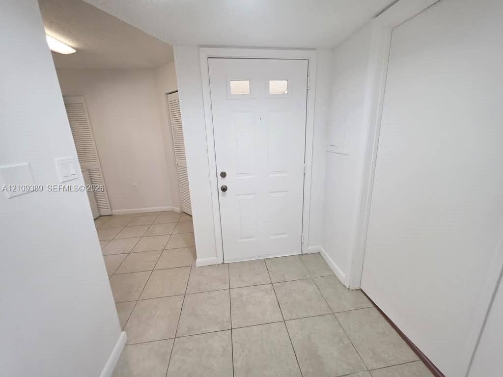 Entry featuring neutral ceramic tile flooring, a multi-panel door with dual light inserts, and dual louvered closet doors