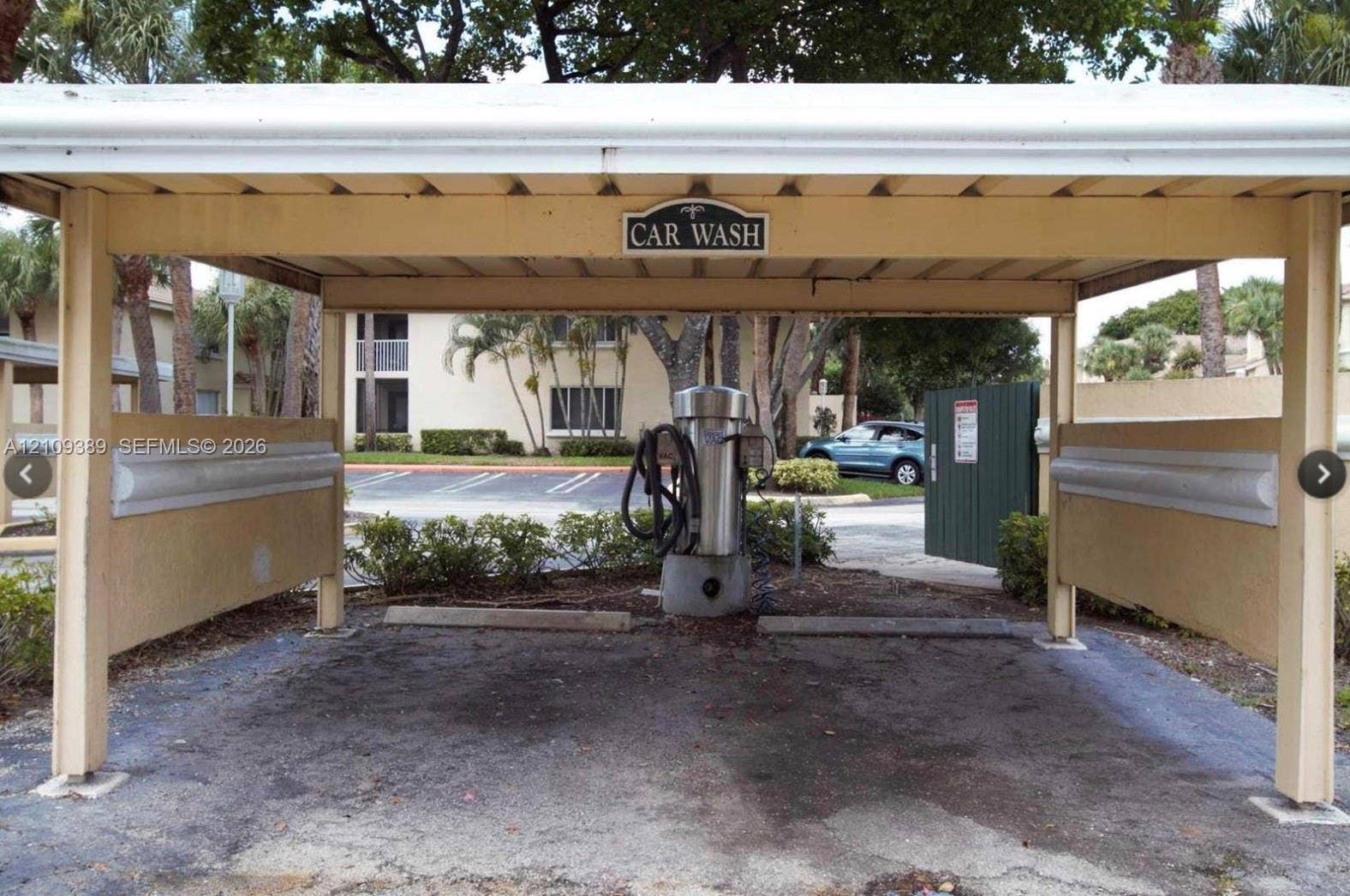 Covered outdoor car wash station featuring an integrated vacuum system and side protection rails
