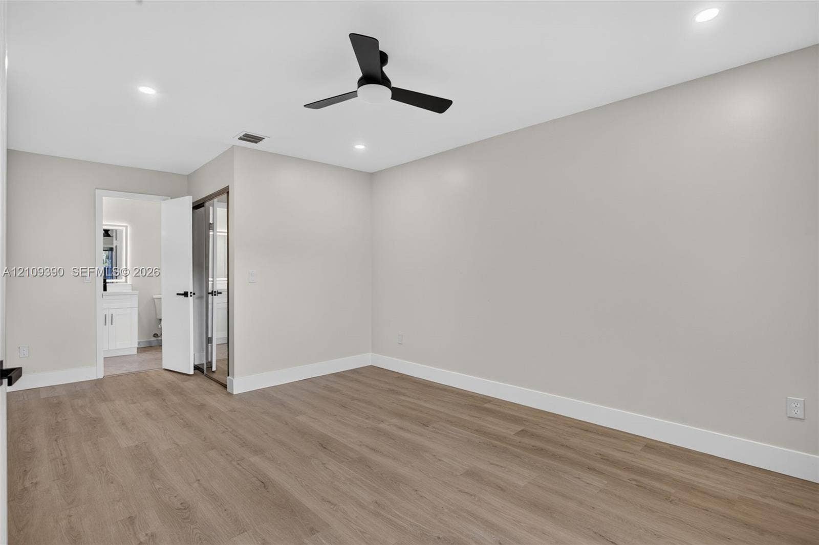 Neutral-toned interior featuring wood-finish flooring, recessed lighting, and a matte black ceiling fan