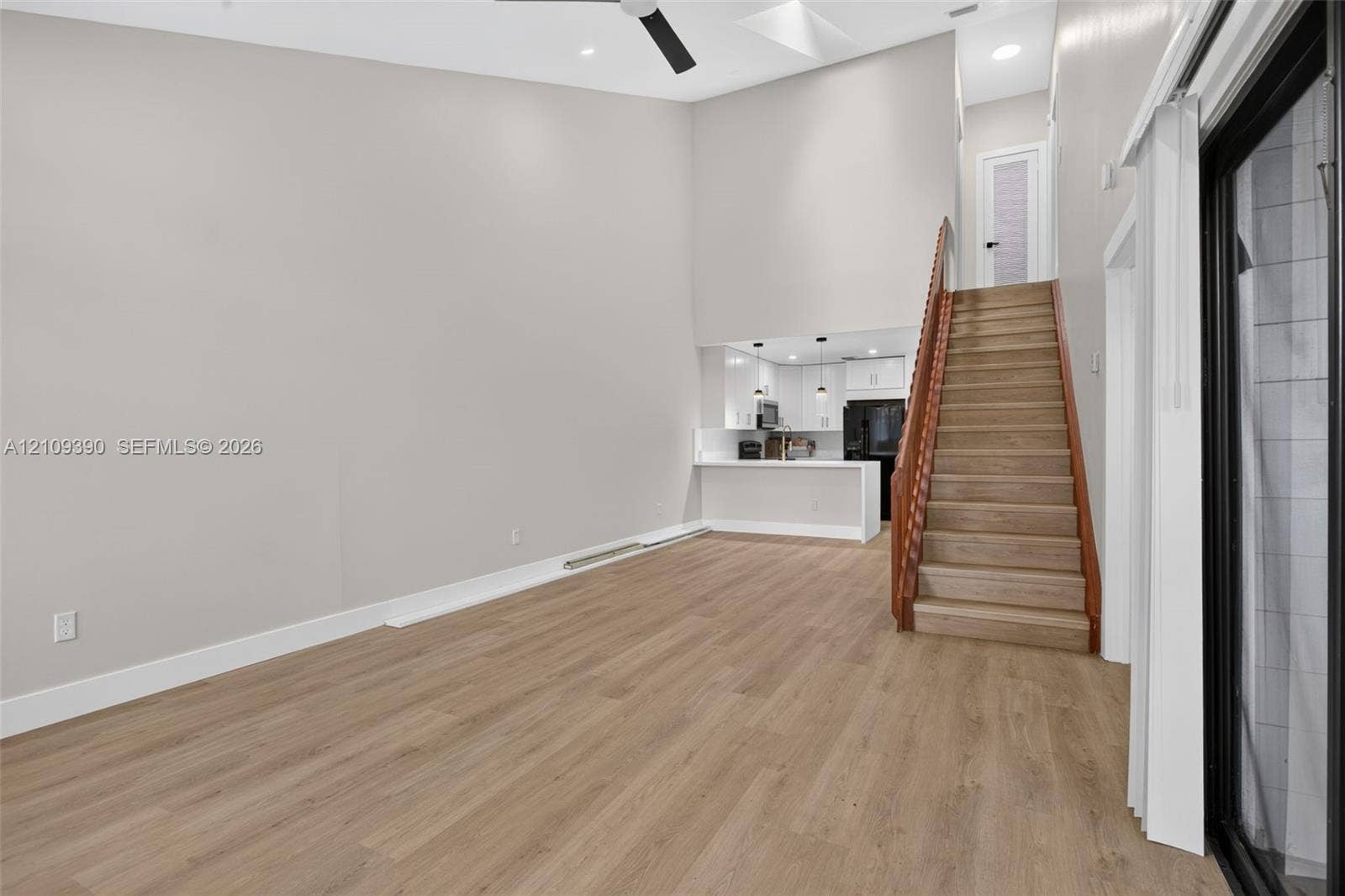 Vaulted ceiling featuring a skylight, wood-finish flooring, staircase with a wood-toned railing, and recessed ceiling lighting
