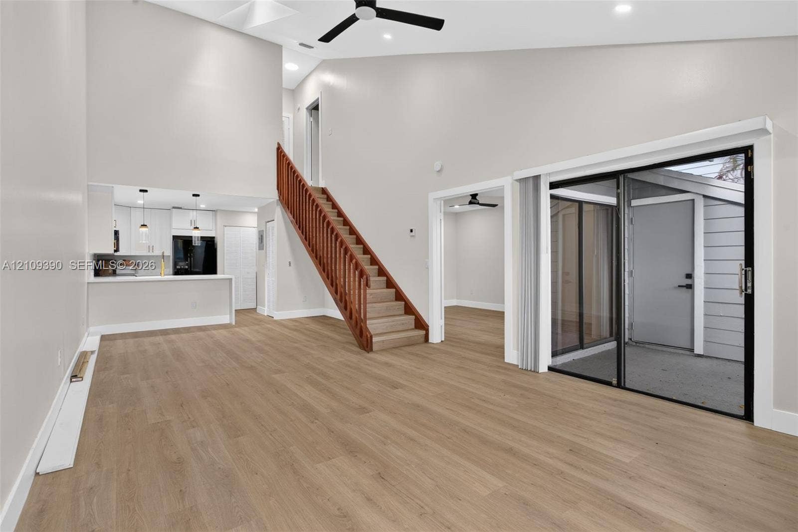 Vaulted ceilings, wood-finish flooring, staircase with a wood railing, sliding glass door, and recessed lighting