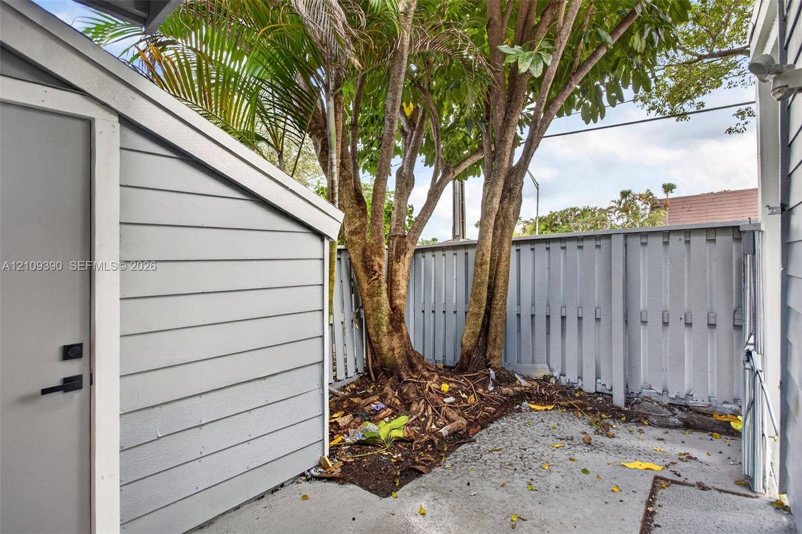 Exterior utility space featuring horizontal lap siding, concrete flooring, and a privacy-style fenced enclosure