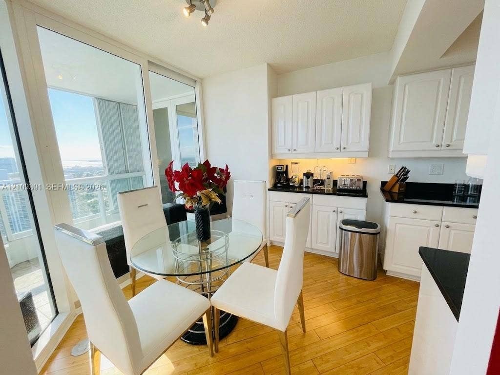 Kitchen featuring white cabinetry, dark stone countertops, wood-finish flooring, and floor-to-ceiling windows
