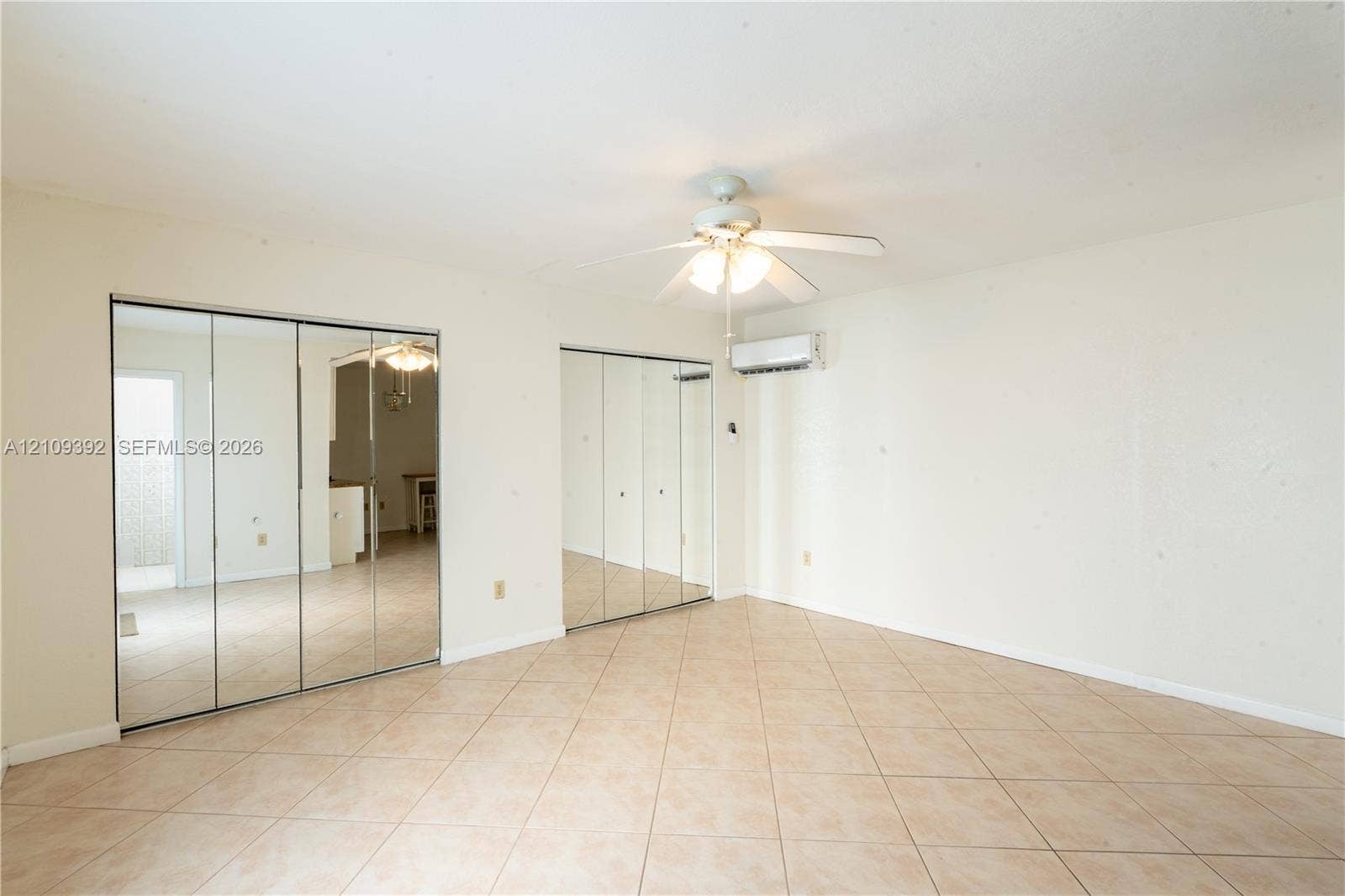 7641 Raleigh Street, #1, Hollywood, Hollywood, FL 33024 Neutral-toned tile flooring, dual mirrored sliding-door closets, ceiling fan with integrated lighting, and wall-mounted climate control unit