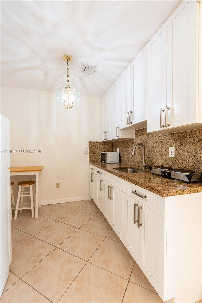 7641 Raleigh Street, #1, Hollywood, Hollywood, FL 33024 Kitchen featuring white shaker-style cabinetry, stone-finish countertops, stainless steel undermount sink with arched pull-down faucet, and neutral tile flooring