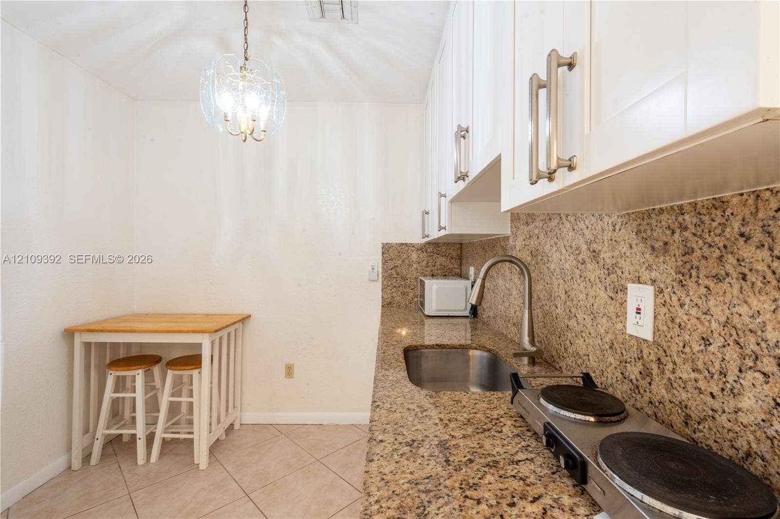 7641 Raleigh Street, #1, Hollywood, Hollywood, FL 33024 Kitchenette featuring white cabinetry with brushed metal hardware, stone-finish countertops, stainless steel sink with high-arc faucet, integrated electric cooktop, and tile flooring