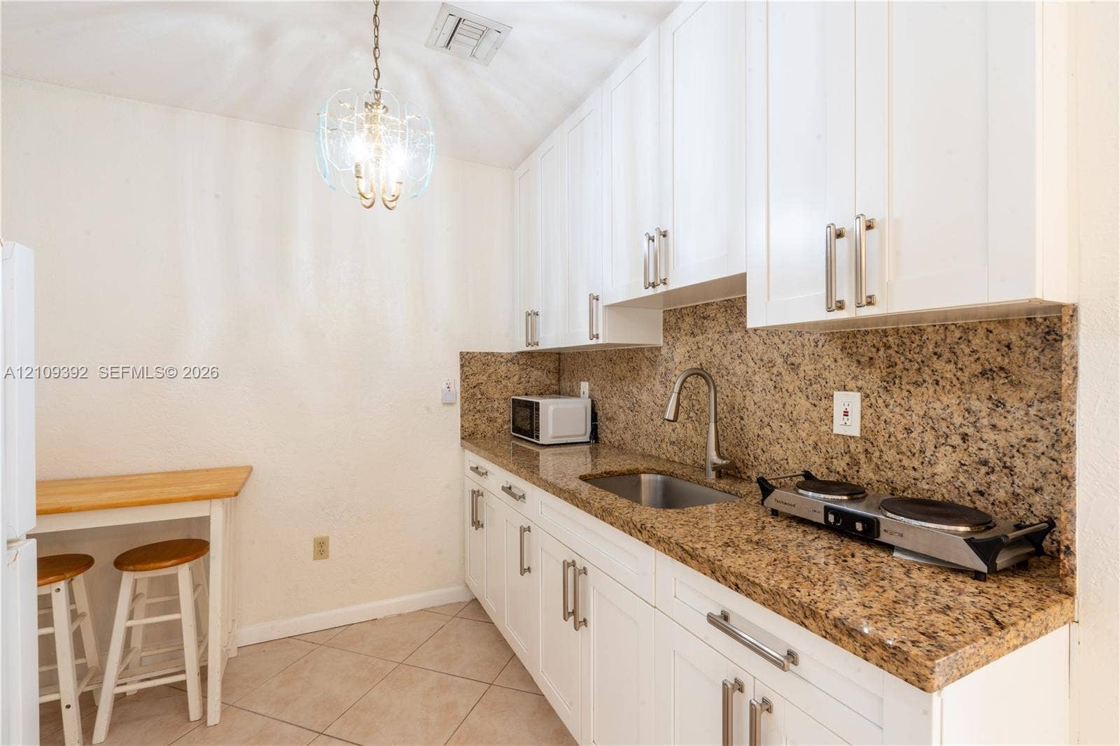 7641 Raleigh Street, #1, Hollywood, Hollywood, FL 33024 Kitchen featuring white cabinetry, stone-surface countertops, tile flooring, an undermount stainless steel sink with a pull-down faucet, and a decorative pendant light fixture