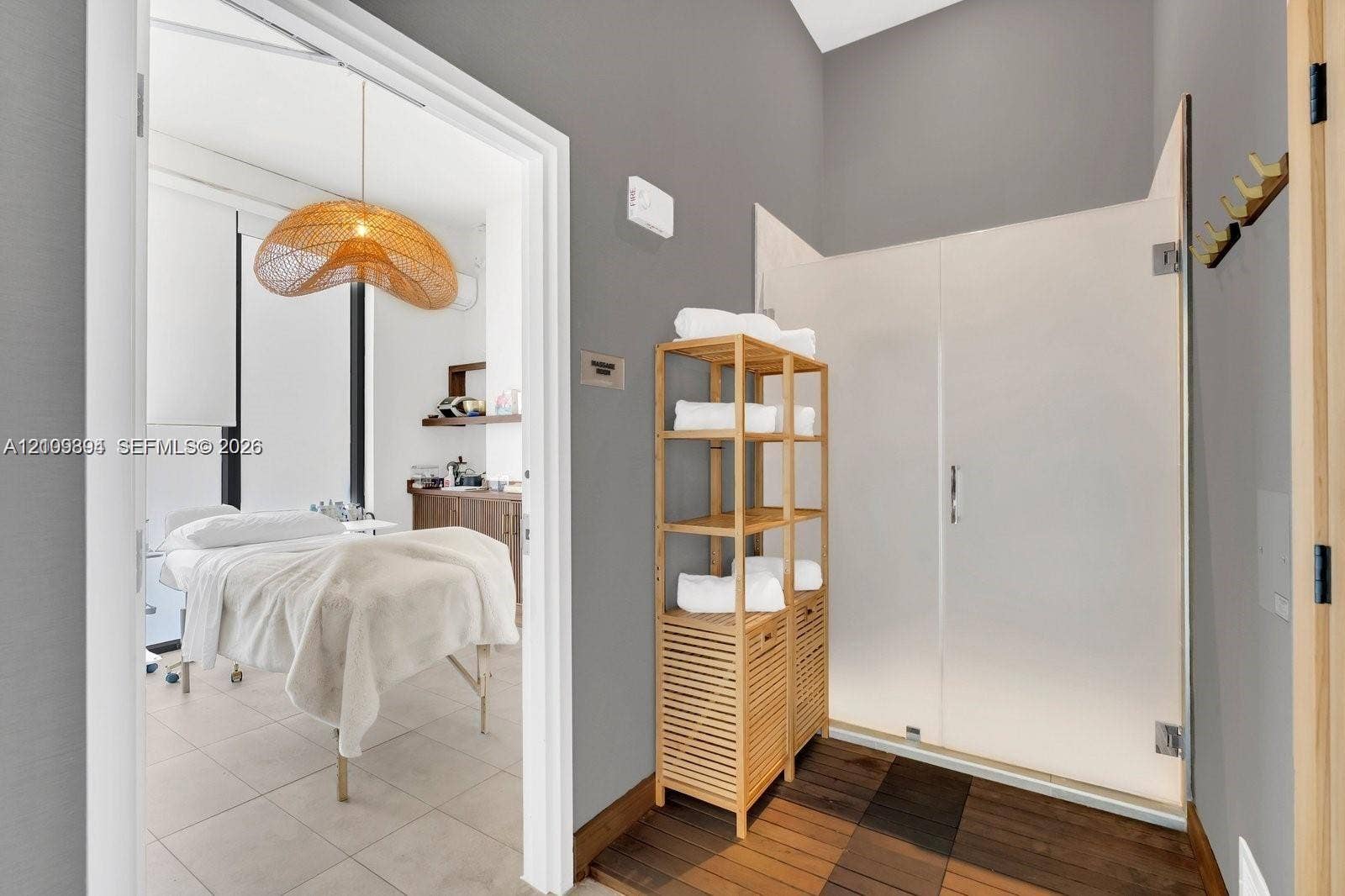 Enclosed shower with opaque glass door, wood-finish flooring, and neutral wall tones