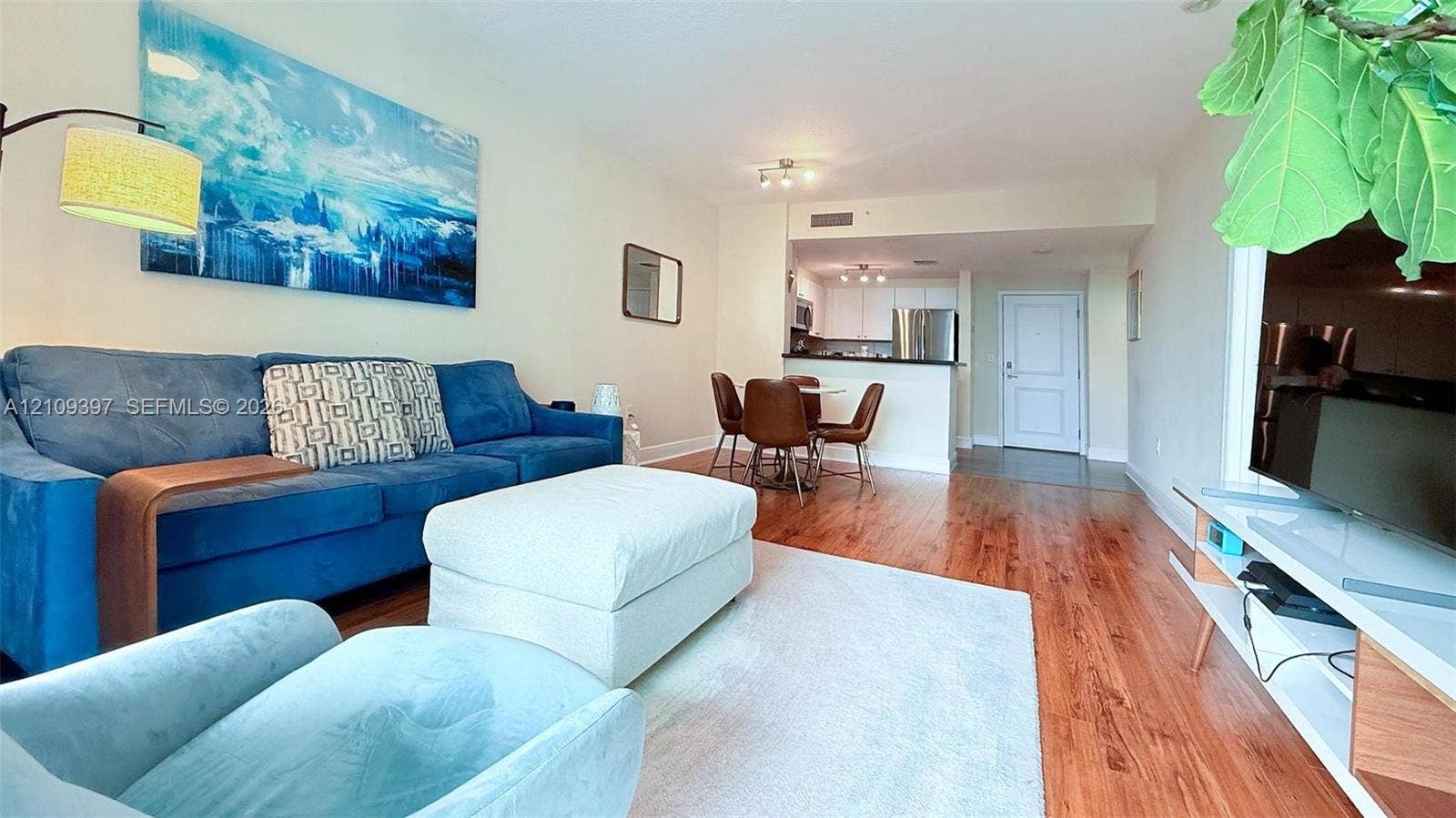Open-concept living space featuring wood-finish flooring, a kitchen peninsula, and a multi-panel door