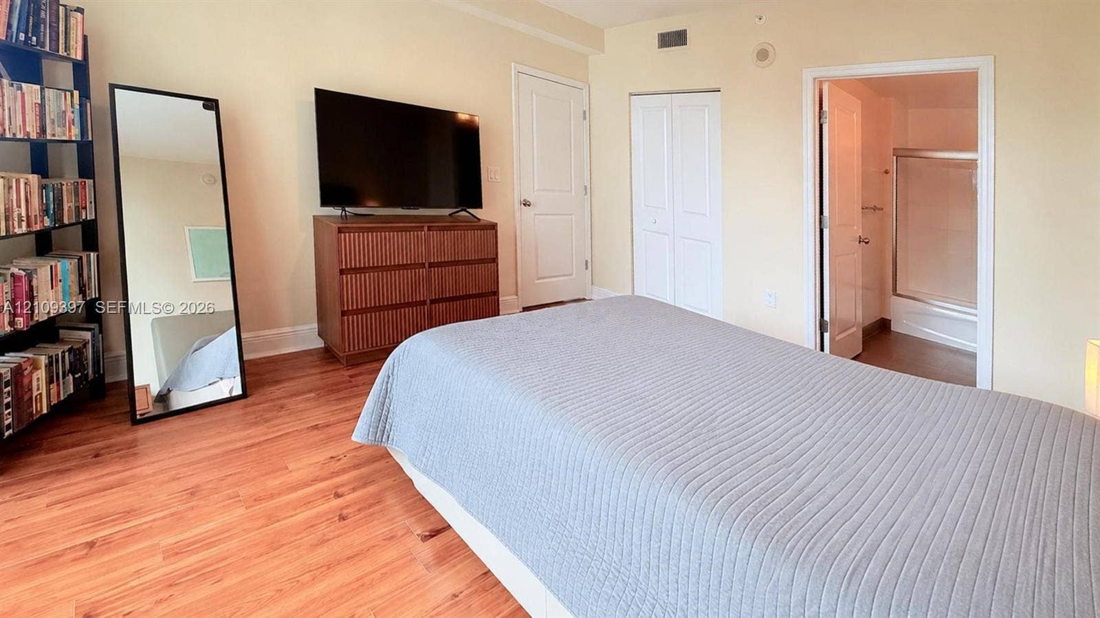 Room featuring wood-finish flooring, two-panel interior doors, and dual-door reach-in closet