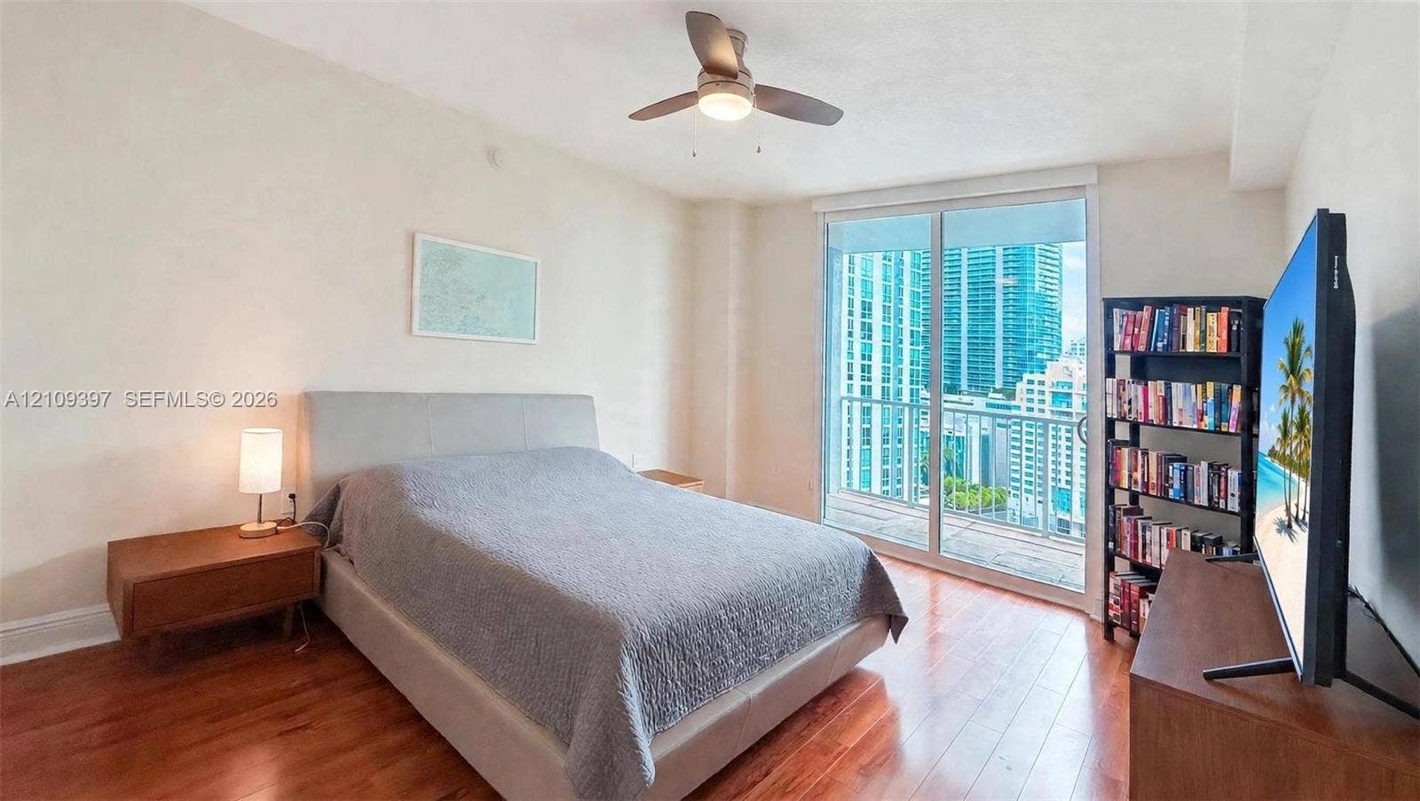 Wood-finish flooring, ceiling fan with integrated lighting, and floor-to-ceiling glass sliding doors opening to a private balcony