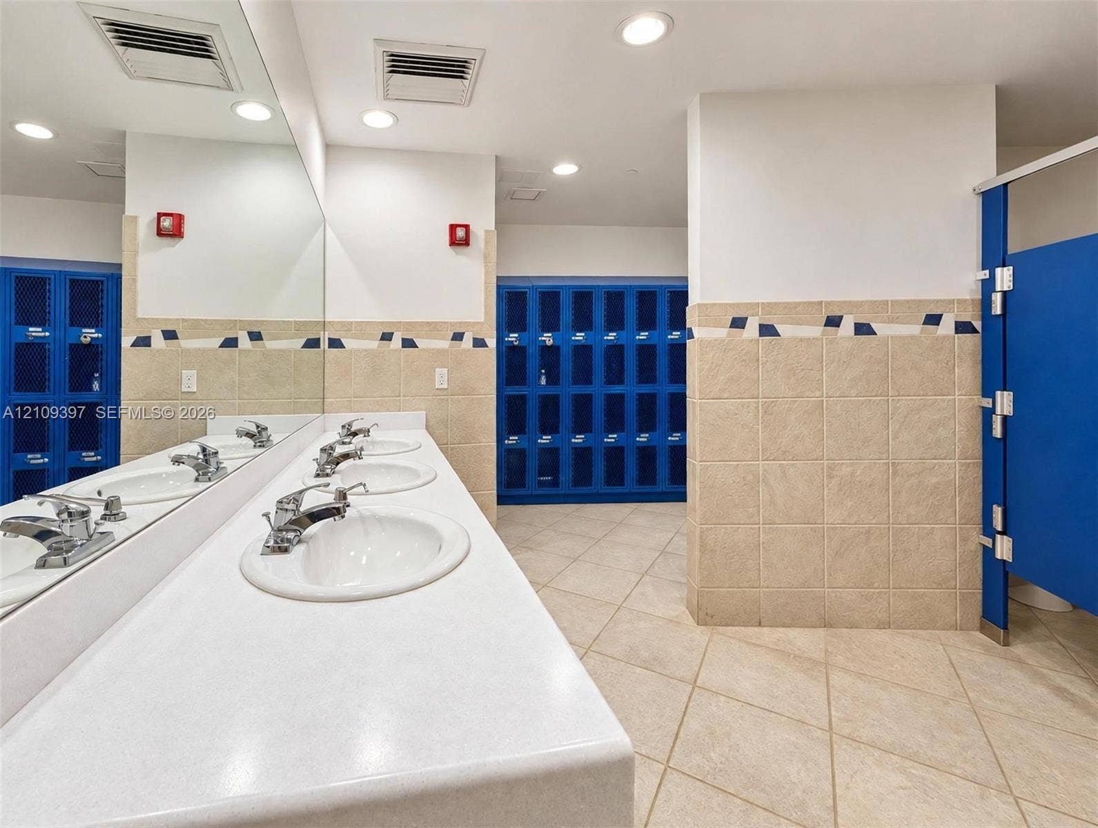 Multi-station vanity featuring white composite countertops, integrated oval sinks, chrome-finish faucets, and a full-width wall mirror