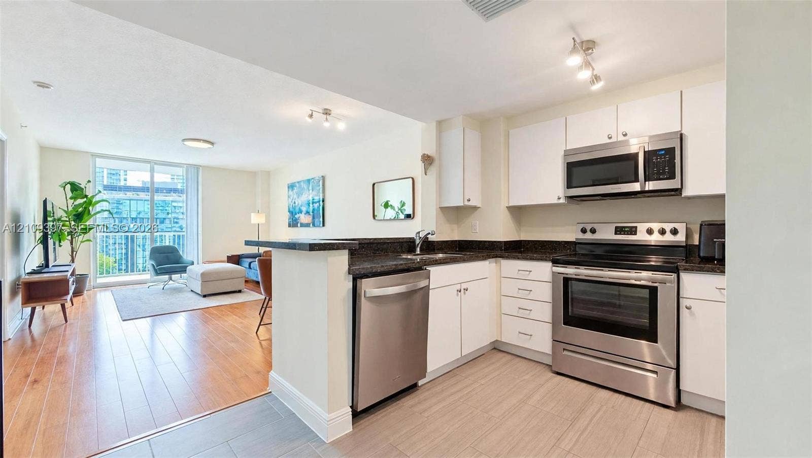 Kitchen featuring stainless steel appliances, dark countertops, white cabinetry, wood-finish flooring, and tile flooring