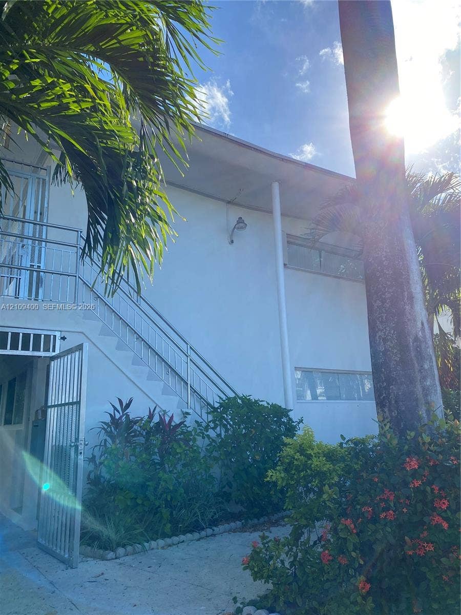 Two-story exterior featuring white stucco siding, metal railing staircase, and horizontal sliding windows