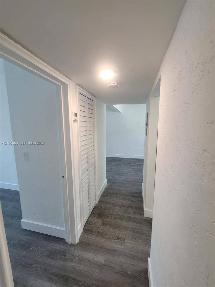 Hallway featuring wood-finish flooring and white louvered closet doors
