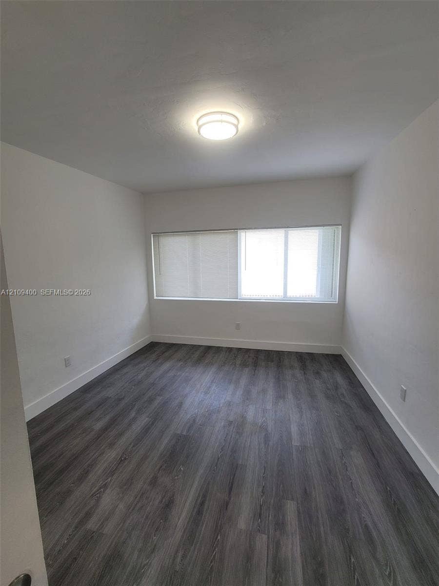 Room featuring wood-finish flooring, neutral walls, a multi-pane horizontal window, and a flush-mount overhead light fixture