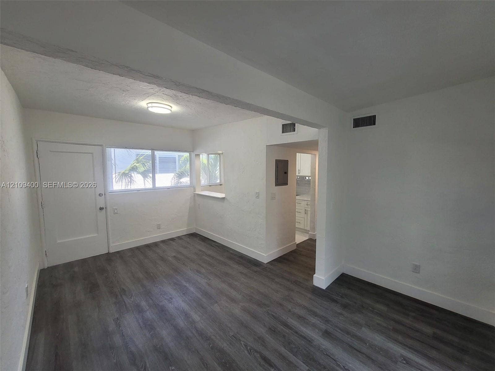 Interior space featuring wood-finish flooring, textured walls, a multi-pane window with a built-in sill, and a recessed ceiling light fixture