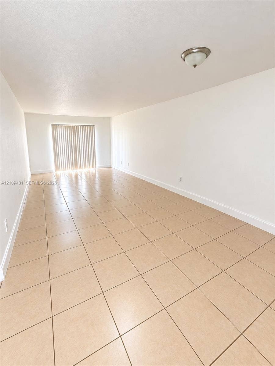 Open floor plan featuring large-format ceramic tile flooring, neutral walls, flush-mount ceiling lighting, and sliding glass patio doors