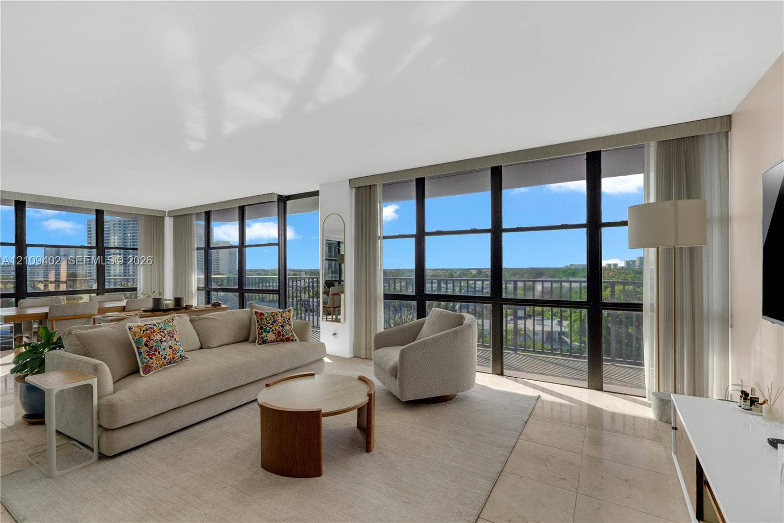 Floor-to-ceiling windows featuring black framing, integrated balcony access, and stone flooring throughout