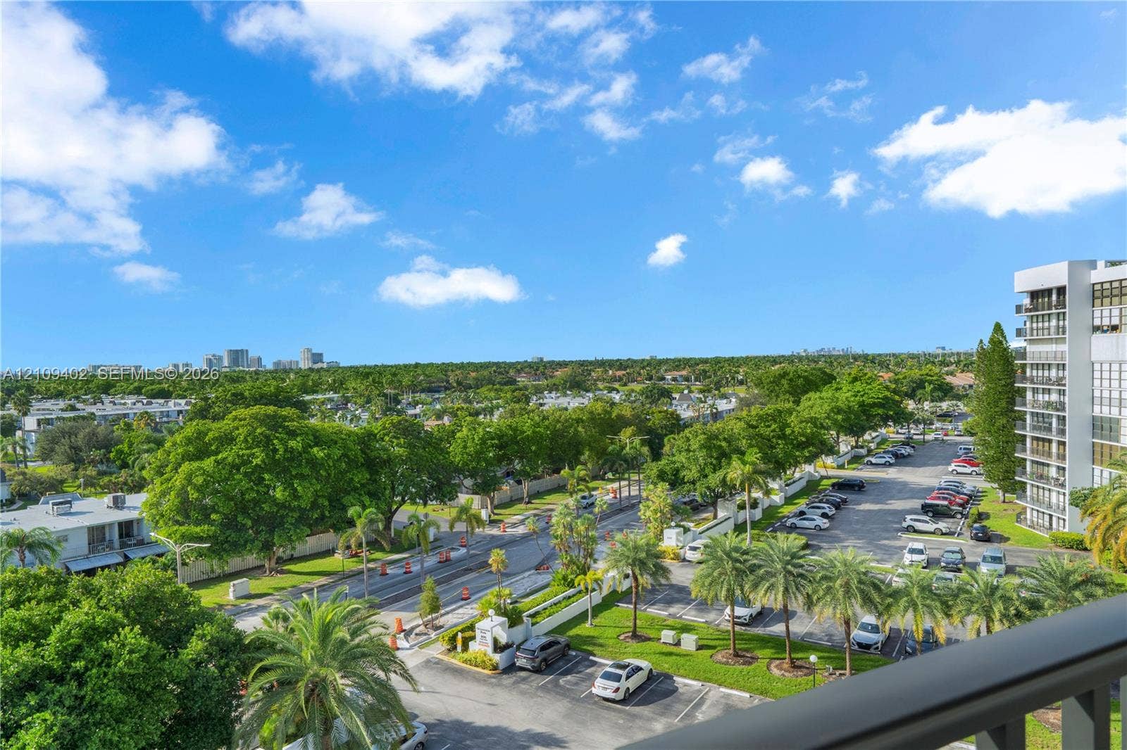Elevated perspective showcasing surrounding tropical greenery, landscaped grounds, and paved parking areas