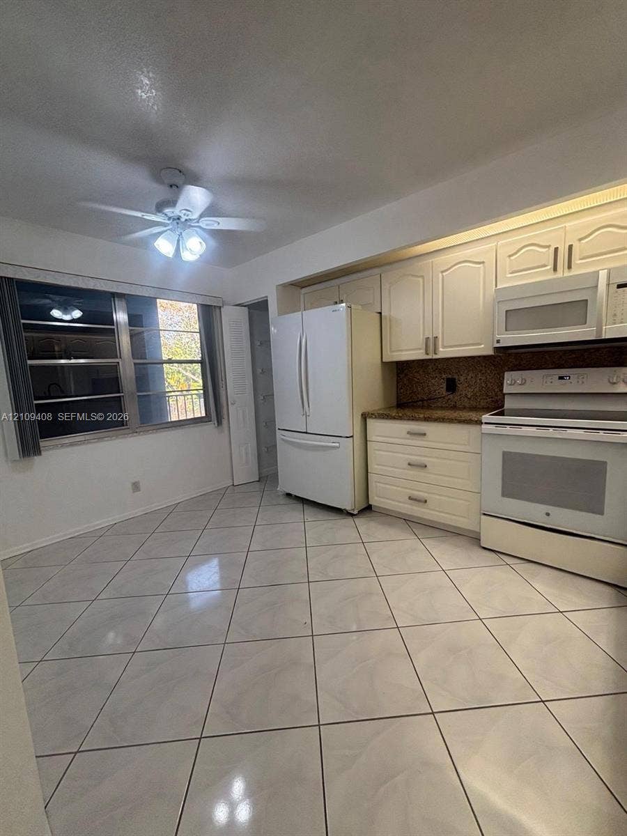 12600 SW 5th Court, #208L, Pembroke Pines, Pembroke Pines, FL 33027 Kitchen featuring white cabinetry, stone-finish countertops, tiled flooring, built-in microwave, and ceiling fan with integrated lighting